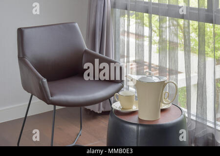 Porzellan Kaffee am Tisch neben Schwarz Leder Stuhl in der Ecke der Wohnzimmer Stockfoto