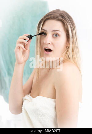Porträt der jungen erstaunt Frau mit offenen Mund tun Make-up im Badezimmer Stockfoto