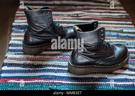 Seitliche Sicht auf zwei robuste, schwarz Knöchel Stiefel aus Leder auf einem bunten Teppich Stockfoto