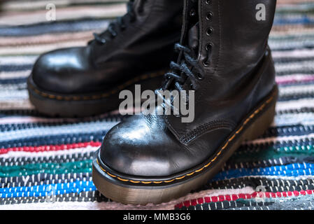 Close-up von zwei robuste, schwarz Knöchel Stiefel aus Leder auf einem bunten Teppich Stockfoto