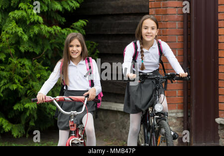 Porträt von zwei Schwestern in Schuluniform auf dem Fahrrad Stockfoto