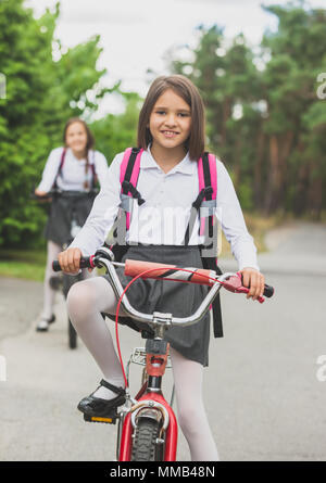 Portrait von schönen Mädchen in Schuluniform und Tasche, mit dem Fahrrad zur Schule Stockfoto