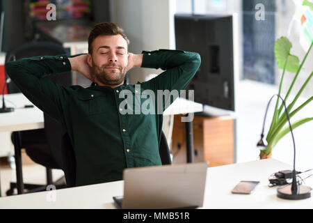 Junge Menschen studieren mit Laptop auf weißem Schreibtisch. Attraktiver Kerl mit Bart legere Kleidung eine Pause. Stockfoto