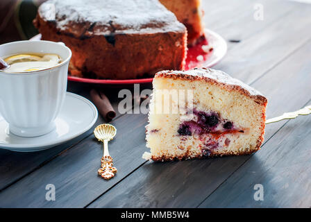 Eine Tasse Tee mit Zitrone und ein Stück hausgemachte Obst und sugare Pulver pie auf dunklem Hintergrund Stockfoto