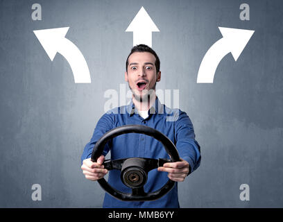 Junger Mann, schwarzes Lenkrad mit drei Pfeilen über seinem Kopf weisen in verschiedene Richtungen. Stockfoto