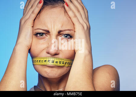 Frau mit einem Klebeband Klebeband auf die Lippen. Sie ist über die Ernährung sorgen. Stockfoto