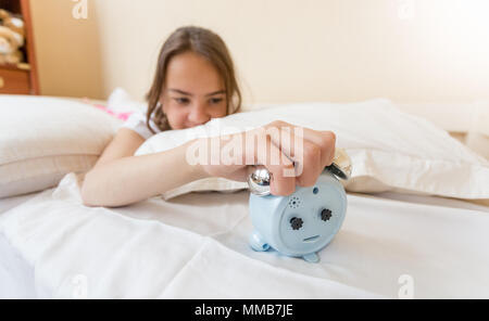 Closeup Bild von wütenden jugendlichen Mädchen liegt auf dem Bett und Ausschalten Wecker Stockfoto