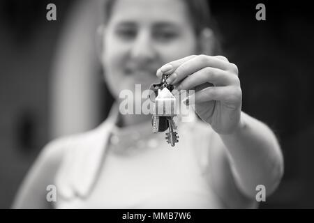 Closeup Schwarz-Weiß-Porträt der lächelnde junge Frau mit Schlüssel aus neues Haus Stockfoto