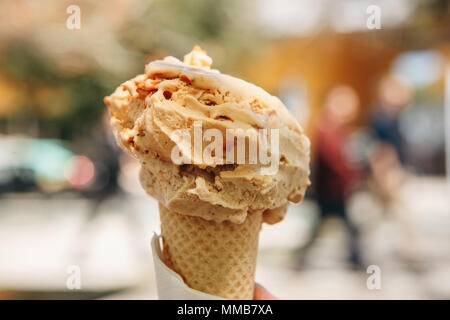Eis in die Hupe im Vordergrund, die Straße ist unscharf im Hintergrund. Süßes und leckeres Essen Stockfoto