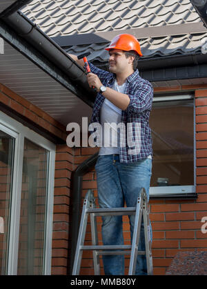 Portrait von lächelnden männliche Tischler macht, das Haus auf dem Dach Stockfoto