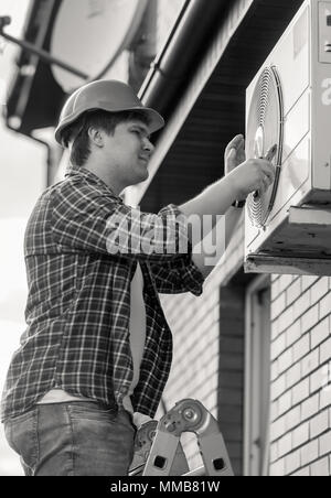 Schwarz-weiß-Porträt von lächelnden techician Instandsetzung der Klimaanlage Stockfoto
