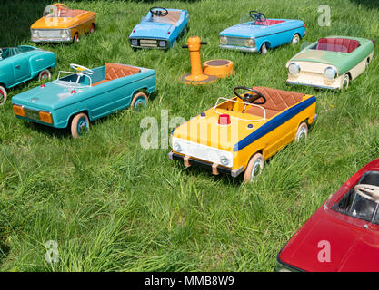 Viele Kinder vintage Spielzeug Tretautos auf grünem Gras am Spielplatz Stockfoto