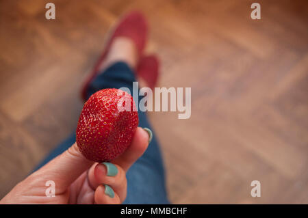 Lady's Hand mit schönen Maniküre Holding eine saftige rote Erdbeere. Stockfoto