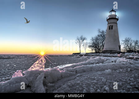 Die historische Marblehead Leuchtturm im Nordwesten von Ohio sitzt entlang der felsigen Ufer des zugefrorenen See Erie. Hier im Winter mit einem farbenfrohen Sonnenaufgang gesehen Stockfoto