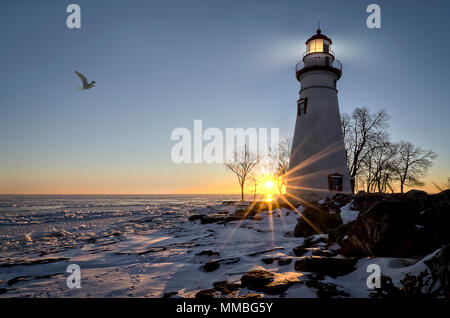 Die historische Marblehead Leuchtturm im Nordwesten von Ohio sitzt entlang der felsigen Ufer des zugefrorenen See Erie. Hier im Winter mit einem farbenfrohen Sonnenaufgang gesehen, Stockfoto