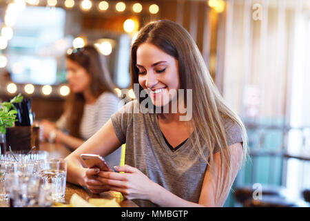 Glückliche Frau sms in Restaurant Stockfoto