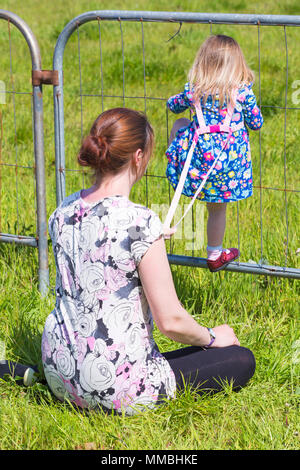 Frau mit Kind klettern herrscht am Zaun im Hampshire Spiel & Country Fair, netley Marsh, Hampshire Großbritannien im Mai Stockfoto