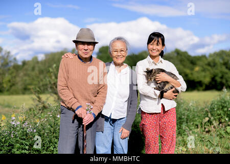 Lächelnde Frau mit graue Katze stehend im Freien, mit einem älteren Mann und Frau, in die Kamera lächeln. Stockfoto