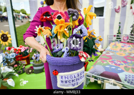 Clare Junge ordnet einen Topf mit verschiedenen gestrickt Blumen in der Arbeit des Herzens Garten', der weltweit erste gestrickt, Garten, während der Rhs Malvern Frühlingsfest an der drei Grafschaften Showground in Malvern, Worcestershire, von Clare Jungen als eine Hommage an ihren Ehemann Ken und das Hospiz, die für ihn gesorgt. Stockfoto