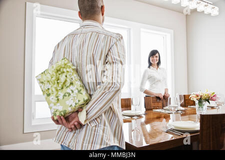 Hispanic Mann über seine Frau eine gewickelt, während im Speisesaal ihres neuen Hauses Stand präsentieren können. Stockfoto