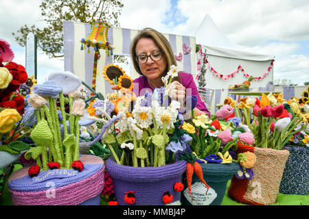 Clare Junge ordnet einen Topf mit verschiedenen gestrickt Blumen in der Arbeit des Herzens Garten', der weltweit erste gestrickt, Garten, während der Rhs Malvern Frühlingsfest an der drei Grafschaften Showground in Malvern, Worcestershire, von Clare Jungen als eine Hommage an ihren Ehemann Ken und das Hospiz, die für ihn gesorgt. Stockfoto