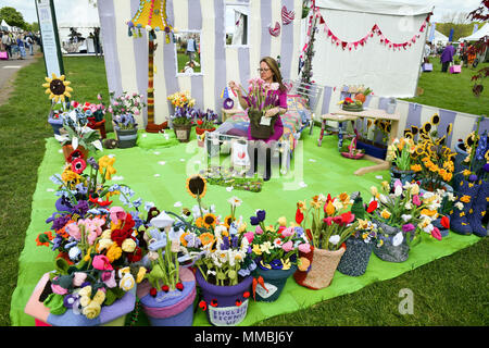 Clare Junge ordnet einen Topf mit verschiedenen gestrickt Blumen in der Arbeit des Herzens Garten', der weltweit erste gestrickt, Garten, während der Rhs Malvern Frühlingsfest an der drei Grafschaften Showground in Malvern, Worcestershire, von Clare Jungen als eine Hommage an ihren Ehemann Ken und das Hospiz, die für ihn gesorgt. Stockfoto