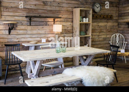 Anzeige der Möbel aus recyceltem Holz, einschließlich der Esstisch mit Sitzbank, Bücherregal und Stuhl, Holzboden und Wand. Stockfoto