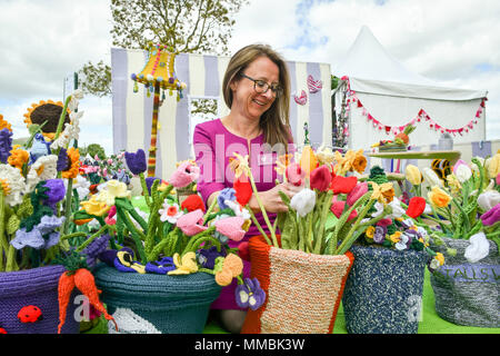 Clare Junge ordnet einen Topf mit verschiedenen gestrickt Blumen in der Arbeit des Herzens Garten', der weltweit erste gestrickt, Garten, während der Rhs Malvern Frühlingsfest an der drei Grafschaften Showground in Malvern, Worcestershire, von Clare Jungen als eine Hommage an ihren Ehemann Ken und das Hospiz, die für ihn gesorgt. Stockfoto