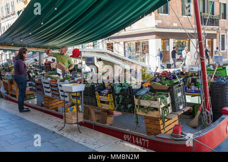 Mann Verkauf von frischen Produkten, Obst und Gemüse, von einem Boot auf dem Rio San Barnaba, Campo San Barnaba, Dorsoduro Venedig, Italien zu einem lokalen Venezianischen woma Stockfoto