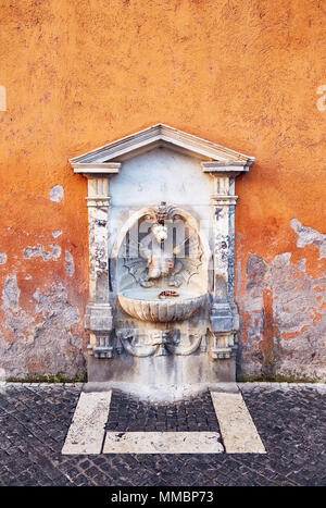 Kleine Trinkbrunnen mit Skulptur und Stein Dekor in schäbigen bemalten Wand, Rom. Stockfoto