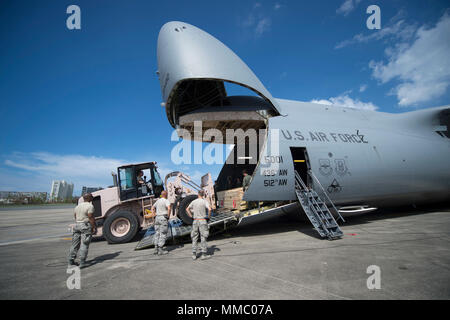 Besatzungsmitglieder Fracht von einem C-5 M Super Galaxy in die 436Th Airlift Wing, Dover Air Force Base, Texas zugeordnet zu entlasten, bei Luis Muñoz Marín International Airport, Puerto Rico, Oktober 6, 2017. Die C-5 M transportiert Türme von AT&T, Telekommunikation mit der Berichterstattung über die Bereiche, in Puerto Rico zu stellen die meisten vom Hurrikan Maria betroffen. Die Initiative ist eine von Präsident Donald Trump Prioritäten für den Wiederaufbau in Puerto Rico. (U.S. Air Force Foto von Tech. Sgt. Larry E. Reid jr., freigegeben) Stockfoto