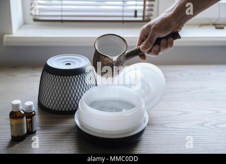 Ein Mann gießt Wasser in den Aroma-Diffusor. Stockfoto
