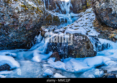 Wasserfall im Schnee mit interessanten Basalt Felsen östlich von Olafsvik, Snaefellsnes, West Island Stockfoto