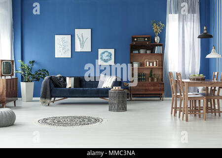 Geräumige Retro Stil Wohnzimmer mit Holzfußboden und blauen Wand Stockfoto