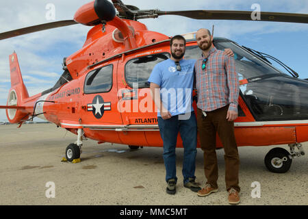 Joe Gottschalk (links) und Billy Gottschalk (rechts) posieren für ein Foto vor der Küstenwache MH-65 Dolphin Hubschrauber, nachdem Sie die Küstenwache öffentlichen Dienst Lob bei Coast Guard Air Station Atlantic City, Okt. 11, 2017 ausgezeichnet wurden. Die Brüder Gottschalk wurden für ihre lebensrettende Bemühungen, wenn sie ihre scanoe gegenüber vier boogie Boarder, die in einem rip Aktuelle in Strathmere, New Jersey gefangen wurden gelenkte gelobt. Die beiden machten sich auf den Weg zu den vier Menschen und gaben ihre Rettungswesten zu zwei Kinder. In Verbindung mit einer Küstenwache Rettungsschwimmerin, alle Boogie b Stockfoto