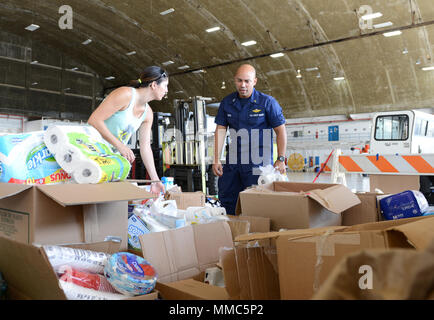 Holly Rivera, deren Ehemann Petty Officer 2. Klasse Bradley Rivera bei Coast Guard Air Station Borinquen in Aguadilla, Puerto Rico, und Leutnant Francisco Muniz Valle, der Kaplan der Air Station Borinquen, Bestand gespendet Hilfe im Hangar der Air Station Okt. 11, 2017. Fast ein Dutzend Mitglieder der Küstenwache ausgeliefert, die gespendeten Beihilfen für Hogar Infantil Jesus Nazareno, ein Waisenhaus, in Isabela, Puerto Rico, ein Bereich, durch den Hurrikan Maria. US beeinflusst Coast Guard Foto von Senior Chief Petty Officer Kyle Niemi Stockfoto