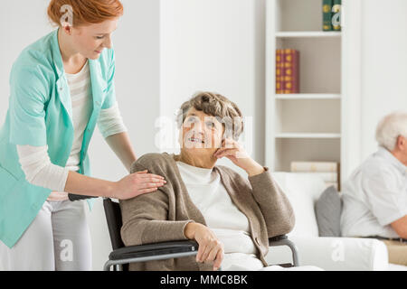 Frau im Rollstuhl auf Ihre junge Krankenschwester suchen Stockfoto