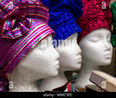 Ein Trio der weibliche Schaufensterpuppe in Brixton, London, UK, shop Fenster anzuzeigen, tragen im afrikanischen Stil Hüte, weibliche Kopfbedeckung, farbenfrohen Stoffen headwear Stockfoto