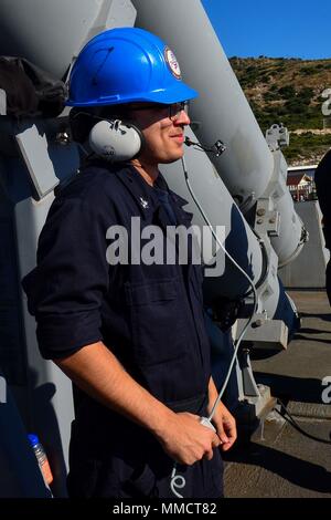 171010-N-QR 145-016 Souda Bay, Griechenland (Okt. 2010) 10, 2017) Brand Controlman 2. Klasse Casey Ross verwendet ein Headset mit Matrosen unter Deck während einer Munition offload an Bord der Arleigh Burke zu kommunizieren - Klasse geführte Anti-raketen-Zerstörer USS Porter (DDG78) in die Bucht von Souda, Griechenland, Oktober 10, 2017. Porter, Vorwärts - Rota, Spanien eingesetzt, ist auf seiner vierten Patrouille in den USA 6 Flotte Bereich der Maßnahmen zur Unterstützung der regionalen Verbündeten und Partner, und die nationale Sicherheit der USA Interessen in Europa. (U.S. Marine Foto von Mass Communication Specialist 3. Klasse Krystina Coffey/Freigegeben) Stockfoto