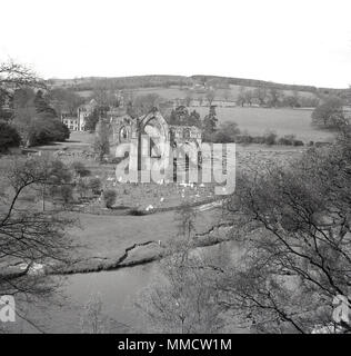 1950, historische, Luftaufnahme über den Ruinen von Bolton Abbey und die umliegende Landschaft, Wharfedale, Yorkshire, England, UK. Der augustinischen Prioy Trümmerstätten. Über eine cementry und die River Wharfe. Stockfoto