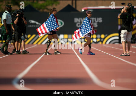 Amerikanische Fahnen drapieren US Air Force Captain Christy Weisen und US Marine Corps Veteran Sarah Ruder auch Sie betreten eine Siegerehrung für die 2017 Invictus Spiele in Toronto, Kanada, Sept. 24, 2017. Die Invictus Games, von Prinz Harry im Jahr 2014 gegründet, vereint die Verwundeten und verletzten Veteranen aus 17 Nationen für 12 adaptive Sportveranstaltungen, einschließlich Leichtathletik, Rollstuhl basketball Rollstuhl Rugby, Schwimmen, Volleyball, und Neu in der 2017 Spiele, Golf. (DoD Foto von EJ Hersom) Stockfoto