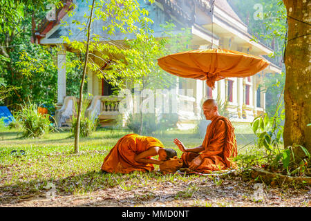 Krabi, Thailand - 2. Mai 2015: Anfänger Mönch anbeten älterer Mönch, unter langstieligen Sonnenschirm in der Nähe von Buddhistischen Kirche in Krabi, Thailand ist Stockfoto