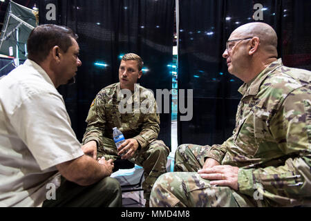 Us-Armee Kapitän Mark Johnston, Chaplin, 14 Combat Support Hospital, Gespräche mit einem lokalen Bewohner, während seine Familie Mitglied wird für eine Kopfverletzung behandelt, als Sgt. Brad Lemky, Behavioral Health, 14. CHS, übersetzt, was Er in Spanisch in Humacao Arena, wo der 14. CHS ihre Feldlazarett in Humacao Puerto Rico, Okt. 18, 2017 Satz sagt. Die 14 CSH ist die lokale Krankenhäuser, deren Fähigkeiten durch den Hurrikan Maria betroffen waren. (U.S. Air Force Foto von Airman 1st Class Nicholas Dutton) Stockfoto
