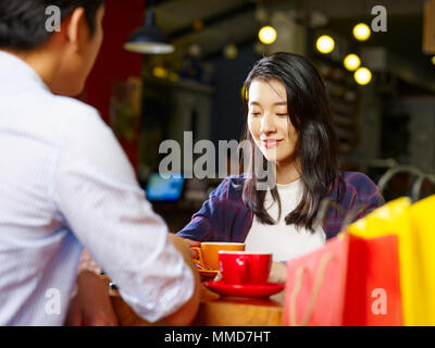 Jungen asiatischen Paar Liebhaber am Tisch sitzen plaudernd im Gespräch in Coffee Shop nach dem Einkaufen. Stockfoto