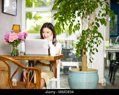 Schöne junge Asiatin im Café sitzen, arbeiten mit Laptop Computer. Stockfoto