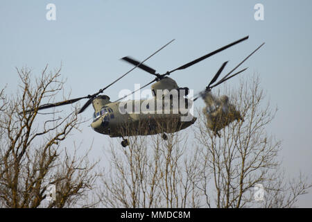 Grafenwöhr, Deutschland - An einem kalten und windigen Nachmittag, CH-47 Chinook Hubschrauber auf das erste Bataillon zugeordnet, 3 Aviation Regiment, 12 Combat Aviation Brigade unterstützt Unternehmen, 2.BATAILLON, 503Rd Infanterie Regiment, 173Rd Airborne Brigade während einem Platoon Level Live Fire Übung an der 7th Army Training Befehl Grafenwöhr Training Area, Deutschland, 20. März 2018. (U.S. Armee Stockfoto