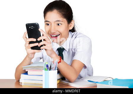 Eine High-School Girl Schüler sitzen At-Table lesen Text-Messaging Handy Stockfoto