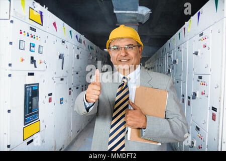 Ein Mann supervisor Holding Zwischenablage angezeigt Thumbs-up in der Nähe der Maschine in der Fabrik - Industrie Stockfoto