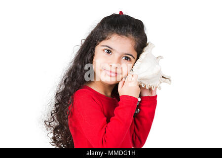 Ein kleines Mädchen Hören von Klängen des Meeres in der muschel Stockfoto