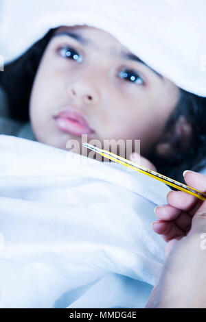 Krankes Kind Mädchen mit hohem Fieber im Bett und Mutter Temperatur prüfen Stockfoto